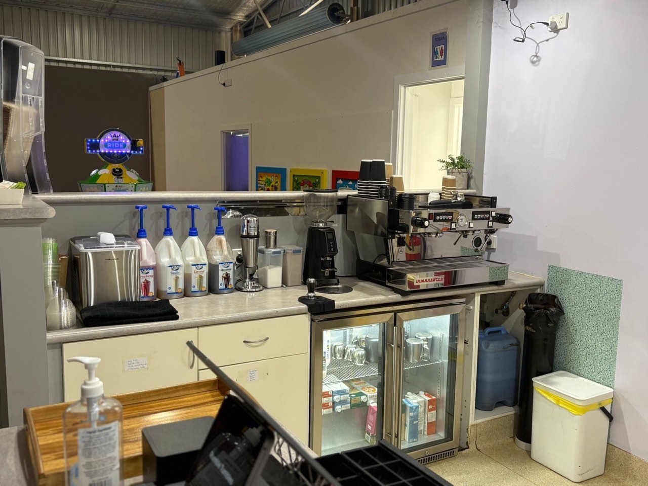 The café counter at Rumble Tumbles with espresso machine, syrups, and fridge