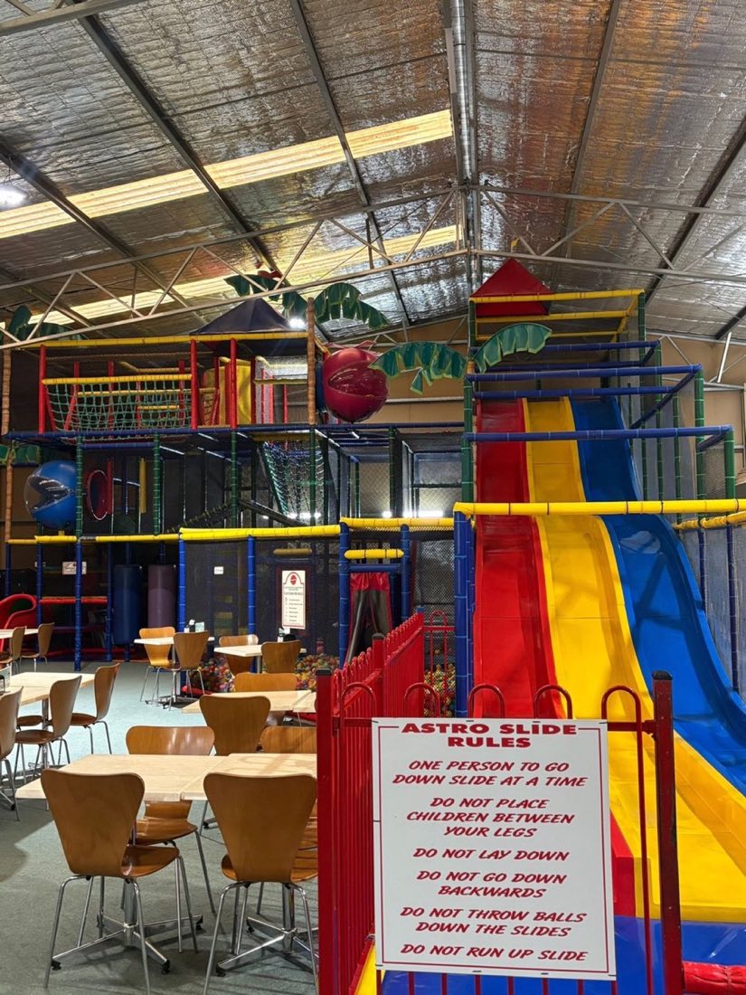 The Rumble Tumbles play floor with café tables in front of the three-storey play structure